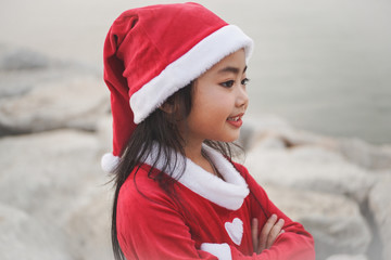 Obraz premium Close-up head shot of Little Asian girl in Santa Claus dress.Be smiling and playing with camera.