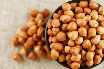Peeled hazelnuts in a wooden, dark brown cup on a burlap cloth. Super Food, Raw.