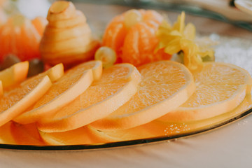 Exquisite cutting of fruit on the holiday table. Bright and colorful tartlets and canapes with oranges, tangerines, grapes and other fruits.