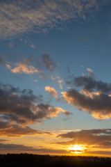 Sunset with rays of sunlight with clouds and blue sky