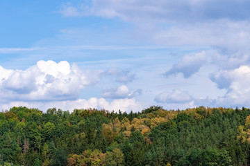 An autumn landscape. A view of the green country agricultural field against stormy blue sky.