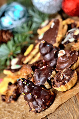 Christmas sweets with different types of candy on baking paper and Christmas decorations in background