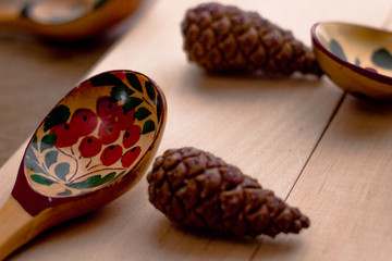 Wood spoon with three cones on wood table near the window