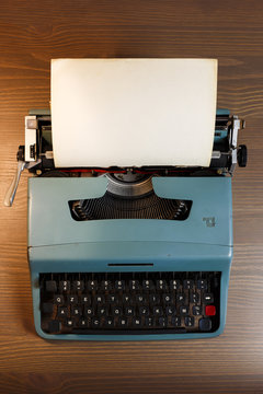 Vintage typewriter header with blank paper on wooden background, top view.