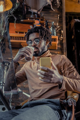 Handsome bearded freelancer drinking cacao in cafe