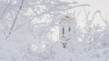 beautiful orthodox white temple among snowy trees in Russia