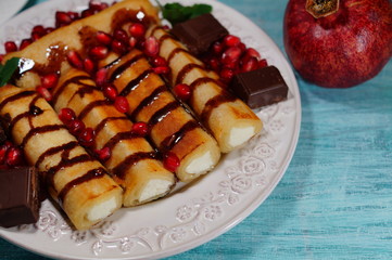 Pancakes with white cheese, chocolate sauce, whole grain granatas and chocolate cubes. Tasty appetizing dessert

