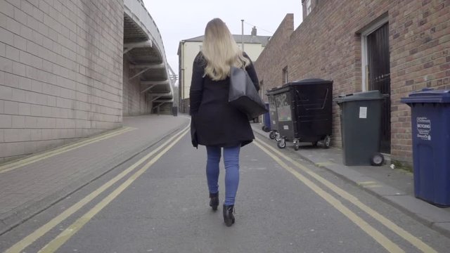 behind following smart casual attractive blonde woman black winter coat walking
