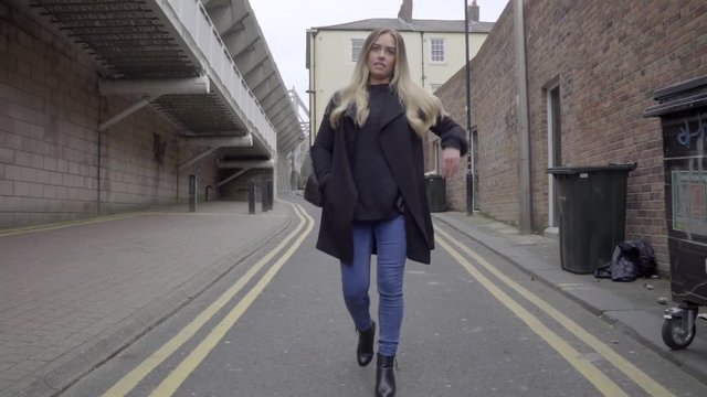 smart casual attractive blonde woman walks alone in alley