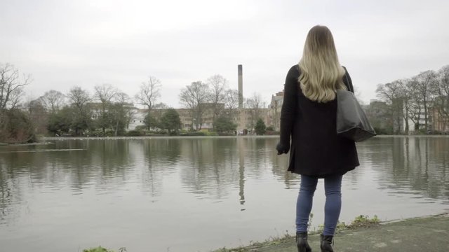 lonely woman looking at city lake winters day