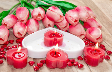 Flowers tulips, a heart-shaped plate and a heart-shaped candle. Festive background to the Valentine's day.