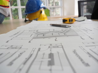 Many of construction drawing paper on the table with yellow anti-knock helmet and other tools