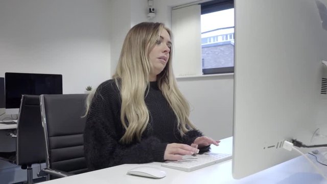 bored tired blonde woman works on computer in office alone