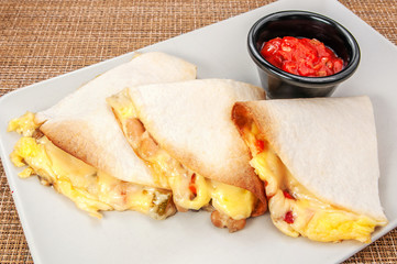 three burrito Burritos wraps with beef and vegetables on white plate with red sauce
