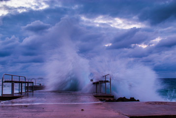 waves from a tropical storm crash down on this concrete dock. The volitile ocean was shot at sunset...