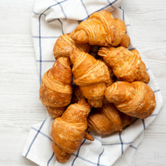 Freshly baked croissants on cloth on white wooden background, top view. From above, overhead, flat...