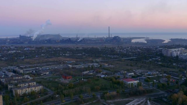 Evening time. Bird's eye view of metallurgical plant. The plant is located in the city by the sea.
