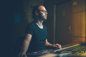 Guy in the studio mixing music on the analog console.
