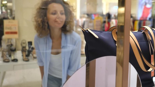 Young Woman Looking At New Bag In Shop Window While Shopping
