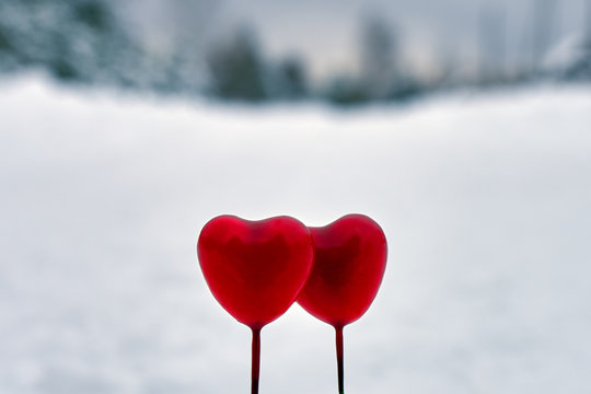 Red Valentine lollipops hearts on the white real snow outdoors