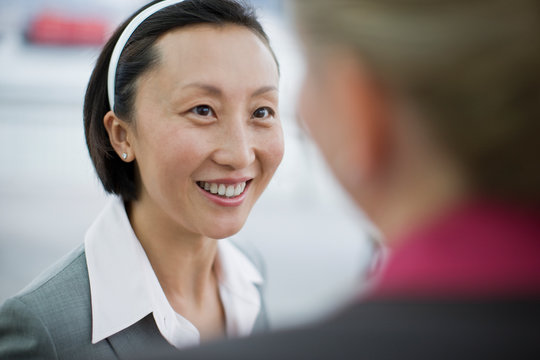 Smiling mid adult businesswoman listening to a female colleague.