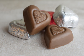 Group of heart chocolates on tan tile.  Close up view.