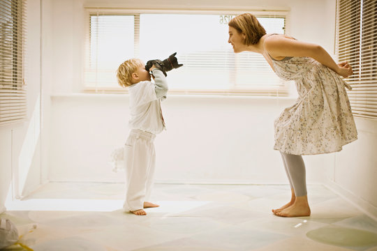Young boy taking a photograph of his mother