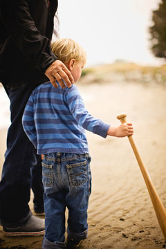 Father and son holding baseball bat on the beach