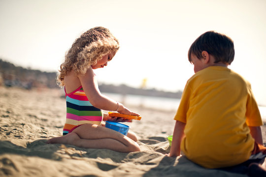 Brother and sister making sandcastles at the beach.