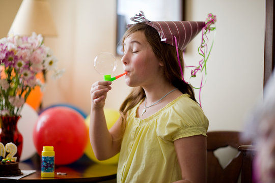 Girl in party hat blowing bubbles