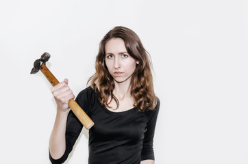 Beautiful girl in a black dress holding a hammer in her hand. Threat, violence, threatens to strike. Hard work, exploitation, release.