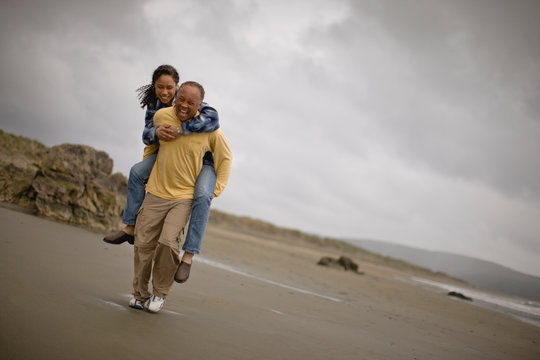 Mature man carrying a woman on the beach