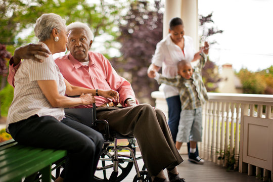 Senior man in wheelchair and family on porch