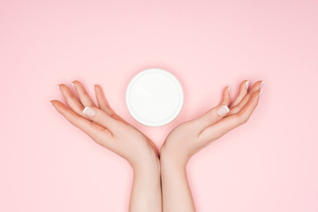 Fototapeta na wymiar cropped view of female hands with body cream isolated on pink