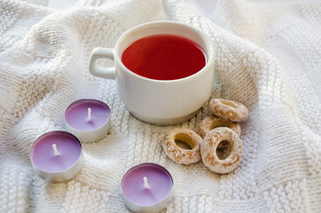 A cup of juice, aromatic candles and bagels on a white background