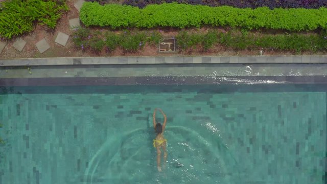 Low Aerial: Beautiful Young Woman in Bikini Entering Swimming Pool
