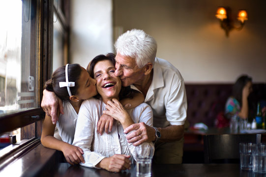 Woman being surprised with a kiss by her husband and her granddaughter.