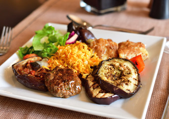 Rice and grilled vegetables and fish on a plate in cafe