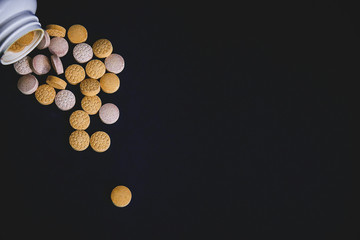 Close up of baby vitamins and supplements, maintain immunity on a dark background with a white bottle. Including vitamin C, Vitamin E, Vitamin D3