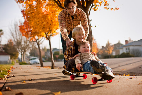 Father pushing boys on skateboard