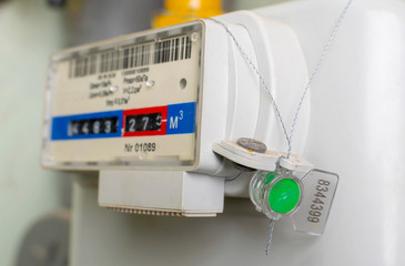 Sealed gas meter hangs on wall. Close-up.