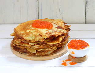 Still life with pancakes and red caviar on a white wooden table