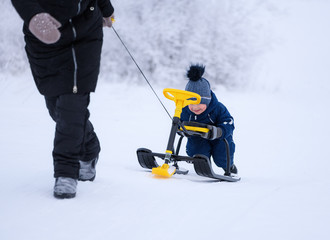 The young woman and her son is on walk in winter. The family activity in outdoors.