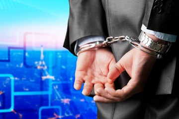 Cropped image of male hands in handcuffs behind his back