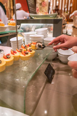 Side view of people choosing Cheese cake in the buffet