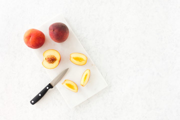 Whole and Cut Amber Blush Peaches on Marble Chopping Board