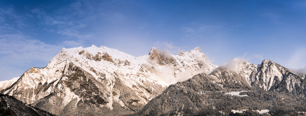 winter mountain landscape with snowy jagged peaks under a blue sky