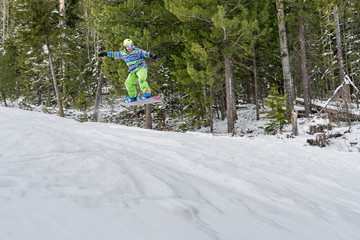 Fototapeta na wymiar Snowboarder jumping in the mountains on a forest background
