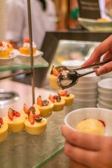 Young man hand taking Cheese Cake in the buffet