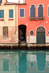 Fototapeta na wymiar Houses reflecting in the narrow canal in Venice, Italy.